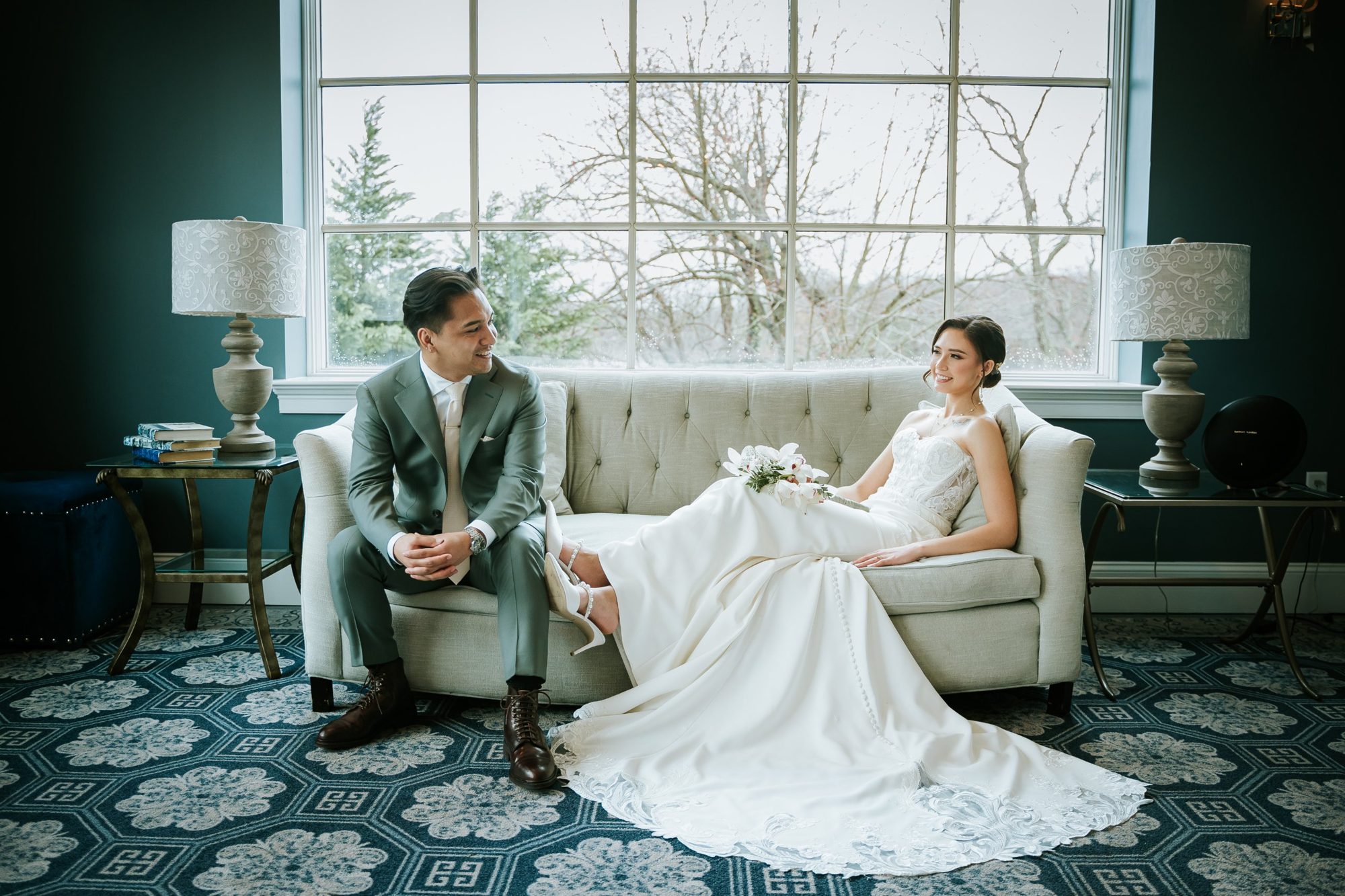Bride and groom relaxing on the tufted sofa in the suite