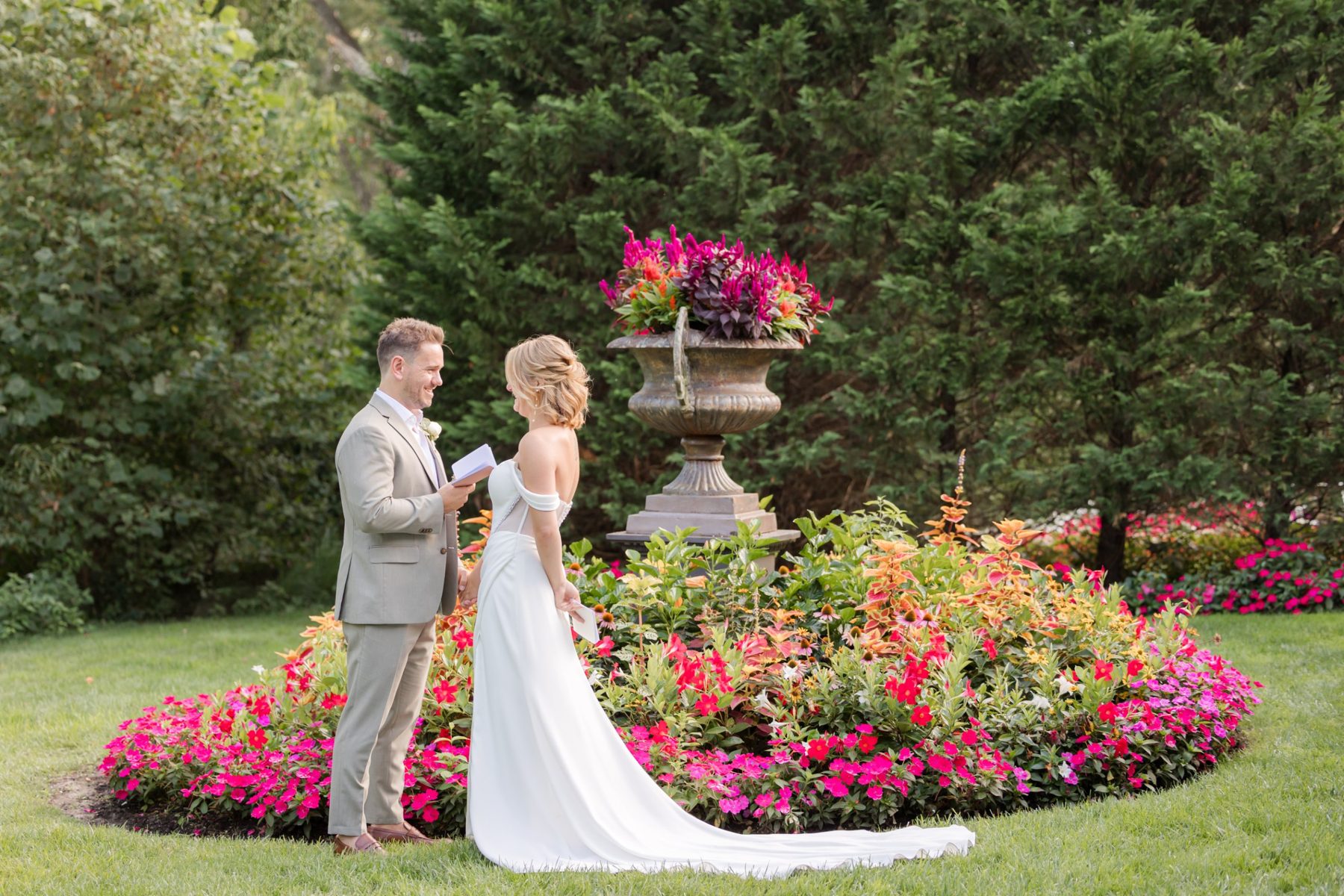 Couple reading private vows beside the garden urn and flowers